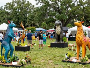 Crowd enjoying SEWE festival with wildlife sculptures and live exhibits.