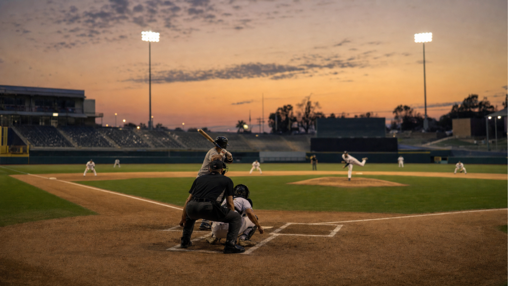 Batter at the plate with catcher and umpire, minor league baseball stadium at dusk